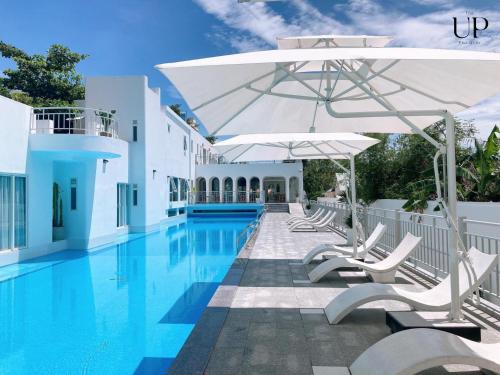 a swimming pool with lounge chairs and an umbrella at The Up Hotel Phu Quoc Island - The Poolside Escape in Phu Quoc