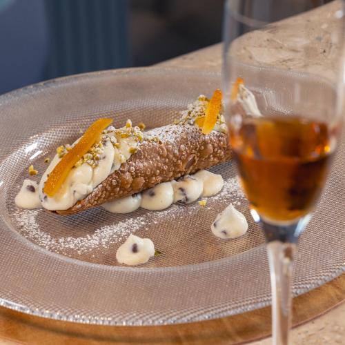 a hot dog on a plate next to a glass of beer at Selinunte Boutique Hotel in Marinella di Selinunte