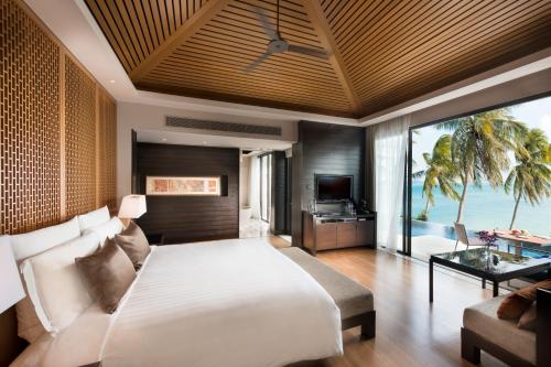 タリンガムビーチにあるConrad Koh Samuiの大きなベッドと海の景色が見えるベッドルーム