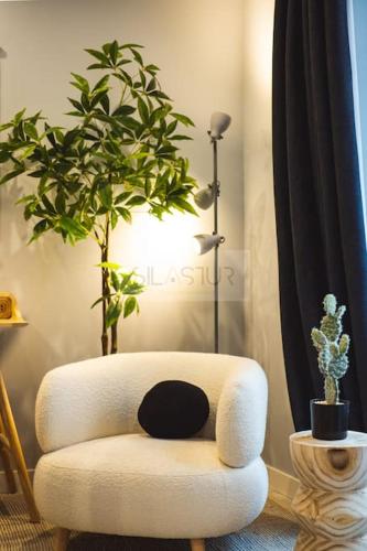 a white chair with a plant in a room at El Bosque Del Puerto in Gijón