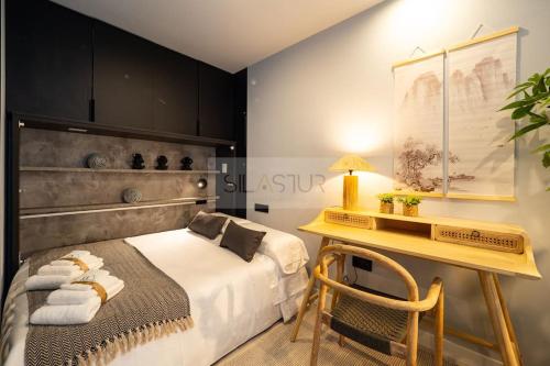 a bedroom with a bed and a desk and a table at El Bosque Del Puerto in Gijón