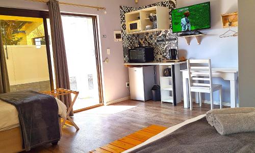 a living room with a table and a desk with a television at Tiende Laan Bed & Breakfast and Self-Catering in Walvis Bay