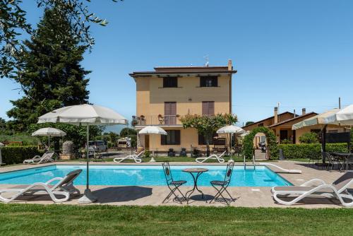 a pool with chairs and umbrellas in front of a building at Agriturismo Il Girasole Assisi in Assisi