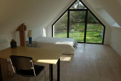une chambre avec un lit et un bureau et une grande fenêtre dans l'établissement Carnac au calme, en pleine foret à 400 m d'un bras de mer, à Carnac