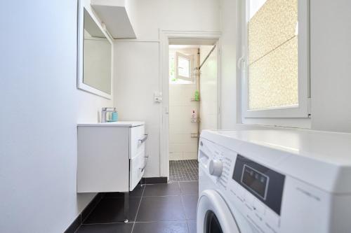 La salle de bains blanche est pourvue d'un lavabo et d'un lave-linge. dans l'établissement Champ Home T2 - 5 mins des Caves de Champagne, à Reims