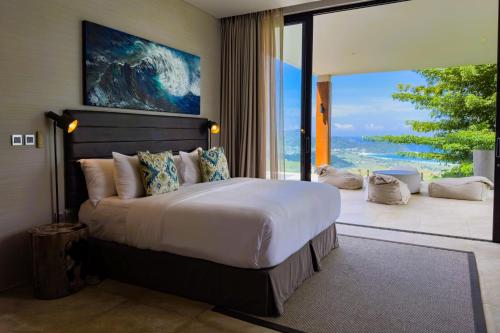 a bedroom with a large bed and a large window at Selong Selo Resort and Residences in Selong Belanak