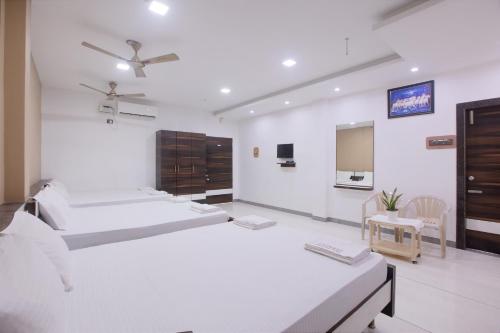 a white room with three beds and a table at Sai Residency in Tiruchchirāppalli