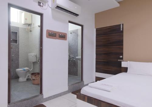 a bedroom with a bed and a bathroom with a toilet at Sai Residency in Tiruchchirāppalli