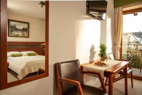 a bedroom with a bed and a table and a mirror at DW Bogun in Białka Tatrzanska