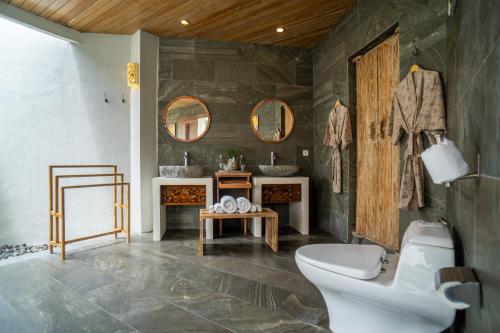 a bathroom with a toilet and a sink and mirrors at Vivara Bali Private Pool Villas & Spa Retreat in Jimbaran