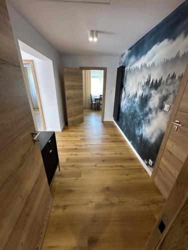 a hallway with wooden floors and a large painting on the wall at Pod Brzozka in Cisna