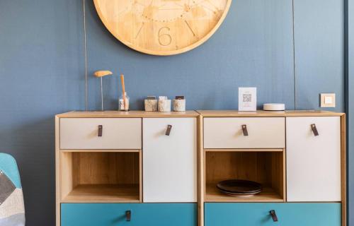 a clock on the wall above two white cabinets at Les Boisés à Kaysersberg+ 1 place de parking in Kaysersberg