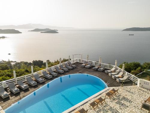 a swimming pool with chairs and a view of the water at Oniro Skiathos in Skiathos Town