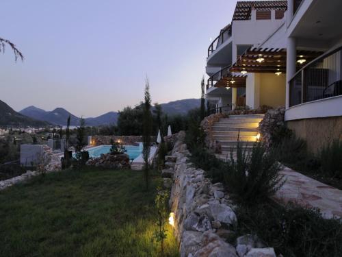 a house with a stone wall next to a swimming pool at Princes ' Islands Luxury Residences in Nydri