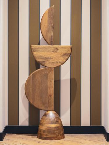 a wooden sculpture on the floor in front of a striped wall at Billie Hôtel in Nantes
