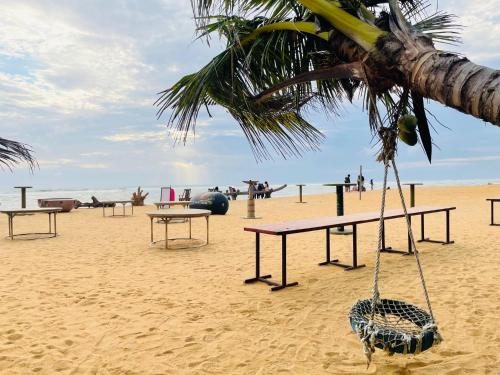 a beach with picnic tables and a swing at Green Star City Apartment in Dehiwala