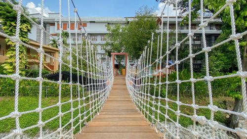 a rope bridge in a garden with a building in the background at Lorin Solo Hotel in Solo