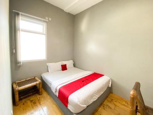 a small bedroom with a bed with a red blanket at RedDoorz near Balai Kota Yogyakarta Timoho in Demangan