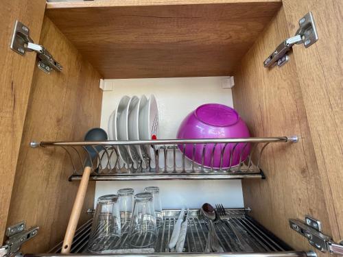 a shelf in a drawer with dishes and a pink bowl at Vogue Rooms in Golem