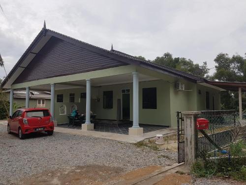a small green house with a red car parked in front at Homestay Ayah Ngah Marang in Marang