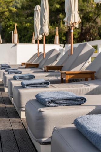 a row of mattresses with umbrellas and tables at Oniro Skiathos in Skiathos Town