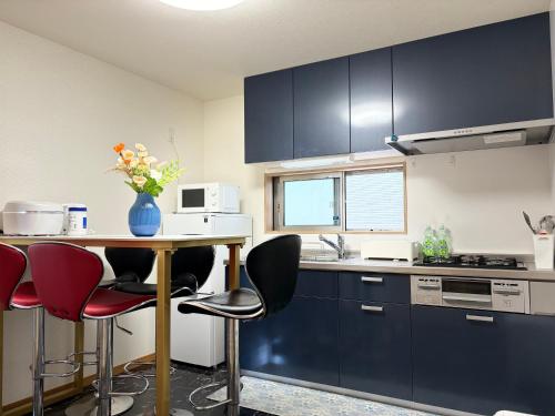a kitchen with black cabinets and a table with red chairs at Lapis House 201 - 2F & 3F in Tokyo
