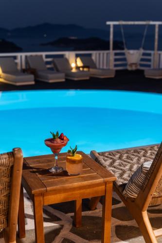 a table with a drink on it next to a pool at Oniro Skiathos in Skiathos Town
