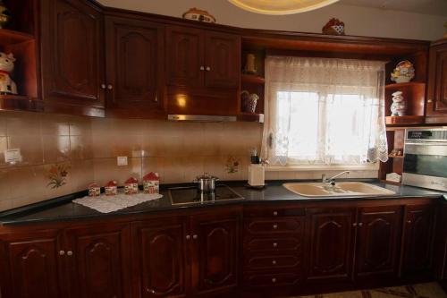 a kitchen with wooden cabinets and a sink and a window at sunrayhouse Arkasa in Arkasa
