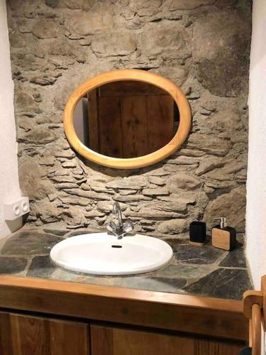 La salle de bains est pourvue d'un lavabo et d'un miroir sur un mur en pierre. dans l'établissement Maison typique rénovée 4 CHBR lac d'Oô Peyragudes, à Oô