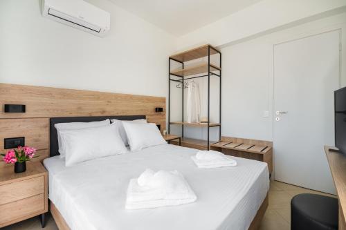 a bedroom with a white bed and a television at Villa Mariani II - in Lothiarika, newly renovated June 2024, private pool, Lindos 10 min, beach 120m in Lardos
