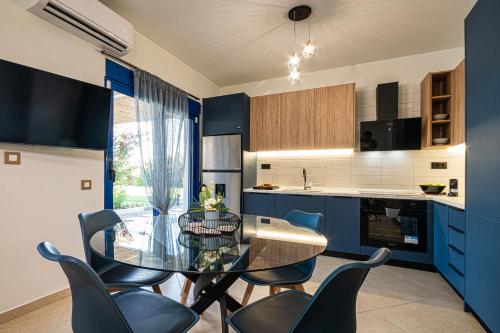 a kitchen with blue cabinets and a glass table and chairs at Villa Mariani II - in Lothiarika, newly renovated June 2024, private pool, Lindos 10 min, beach 120m in Lardos