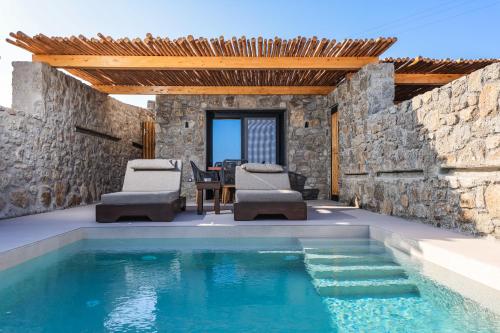 a swimming pool with chairs and a table and a house at Queen Kalliopi Suites in Plintri