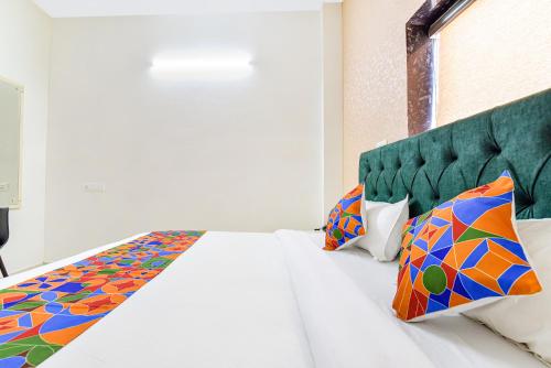 a bedroom with a white bed with a green headboard at FabHotel Prince 24 in Mohali