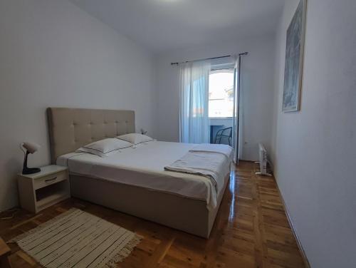 a white bedroom with a large bed and a window at Apartment Nea Zadar in Zadar