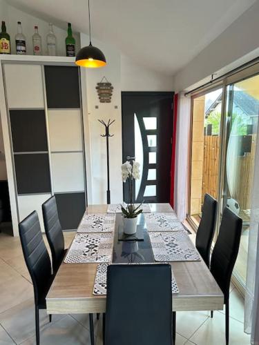 une table à manger avec des chaises noires et une table avec des fleurs. dans l'établissement Made in Beaufort, à Beaufort-en-Vallée