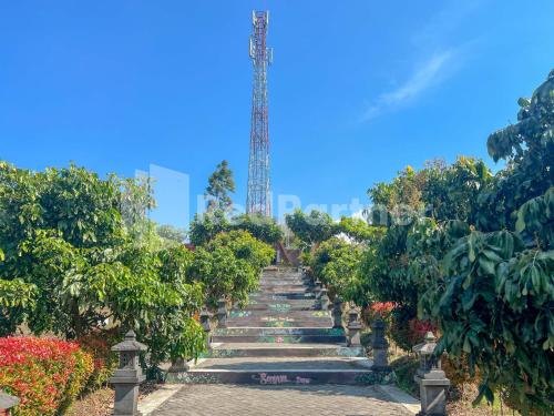 a garden with a staircase with plants and a tower at Glamping Pengilon Edupark Mitra RedDoorz in Temanggung