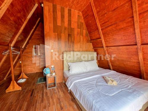 a bedroom with a bed in a wooden cabin at Glamping Pengilon Edupark Mitra RedDoorz in Temanggung