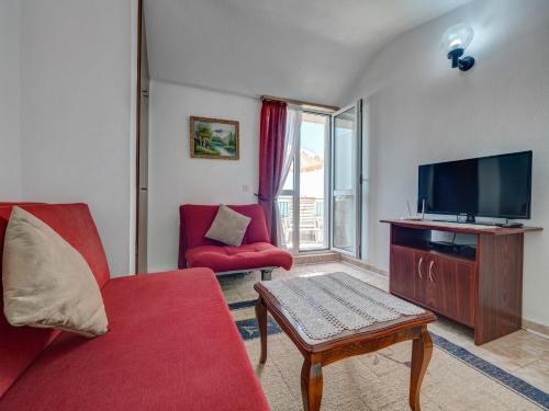 a living room with a red couch and a tv at Apartments Marina in Sveti Stefan