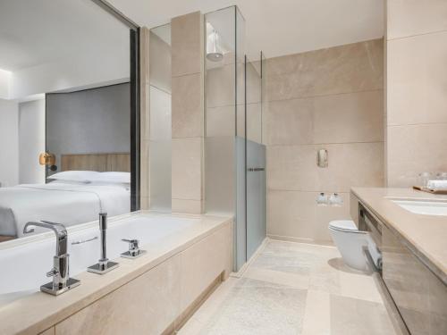 a bathroom with a shower and a toilet and a bed at Sheraton Guangzhou Hotel in Guangzhou