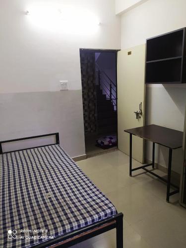 a room with a bed and a table and a door at Khalsa boys residency rajeev gandhi nagar in Kota