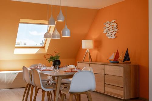 a dining room with orange walls and a table and chairs at Huswell - Cozy seaside apartment with sunny terrace in Blankenberge