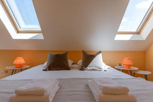 a bedroom with a bed with two skylights at Huswell - Cozy seaside apartment with sunny terrace in Blankenberge