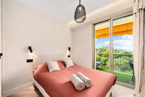 une chambre avec un lit et une grande fenêtre dans l'établissement L'OREE DU CAP-Somptueux 2 pièces- Garage- Terrasse, à Roquebrune-Cap-Martin