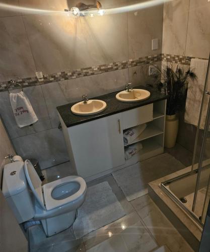 a bathroom with a toilet and two sinks in it at The Royal Princess B&B on Malibongwe Drive in Johannesburg