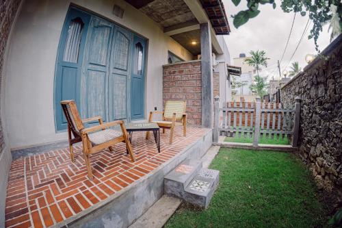 a porch with chairs and a blue door on a house at Still Waters Artistry in Negombo