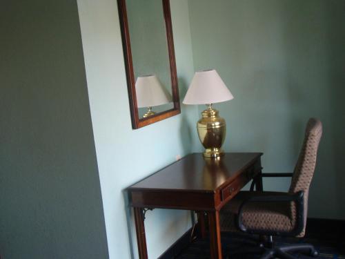 a desk with a lamp and two chairs in a room at Budget Inn Mount Airy in Mount Airy