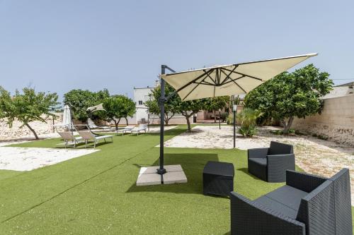 a patio with chairs and an umbrella on the grass at Pietramare Luxury Suites in Bari
