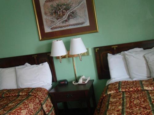 two beds in a hotel room with two lamps and a phone at Budget Inn Mount Airy in Mount Airy