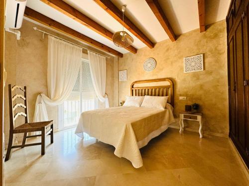 a bedroom with a bed and a chair and a window at Casa Familiar- Residencial Solmar in Sanlúcar de Barrameda
