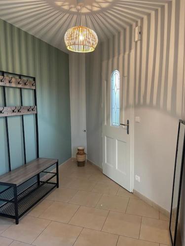 a room with a door and a bench and a chandelier at Gite de Morlannes - Nogaro, Barbotan in Marguestau